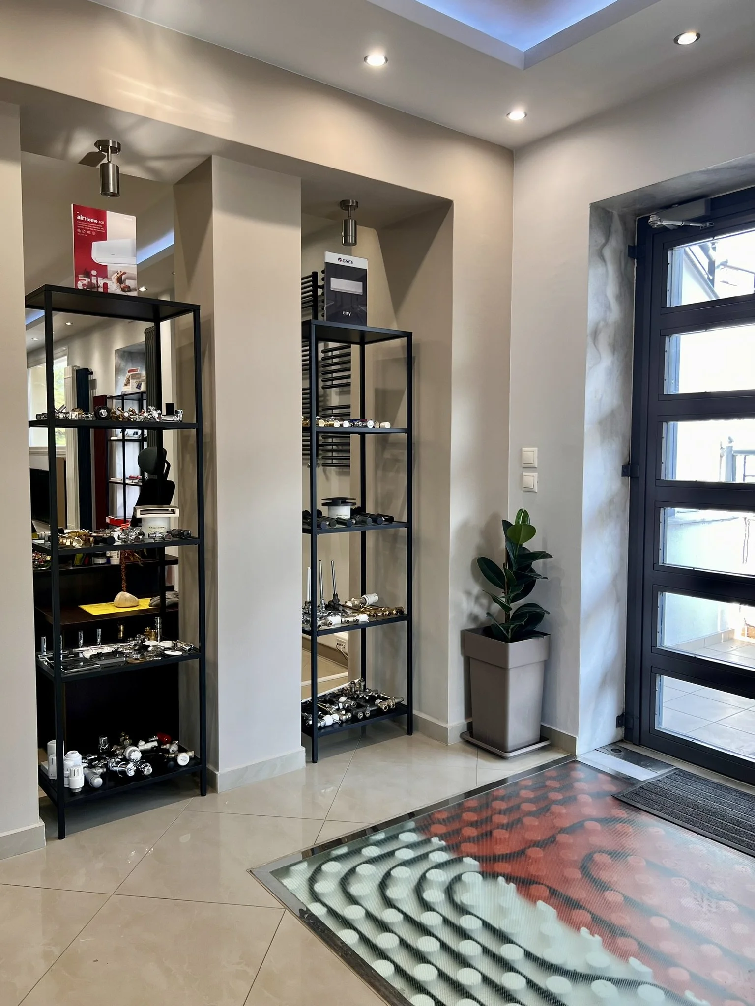 Tsolakidis store display featuring various radiator valves in different colors and a functional underfloor heating demo