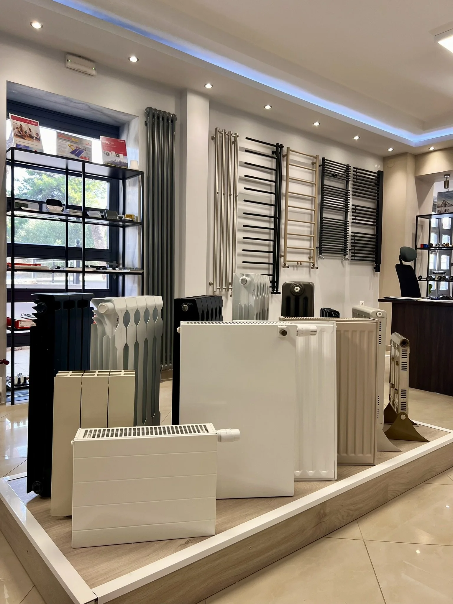 Interior view of the Tsolakidis showroom featuring a wide selection of modern decorative radiators, including vertical heating panels, mirror-style radiators, and colored designer units for both living spaces and bathrooms