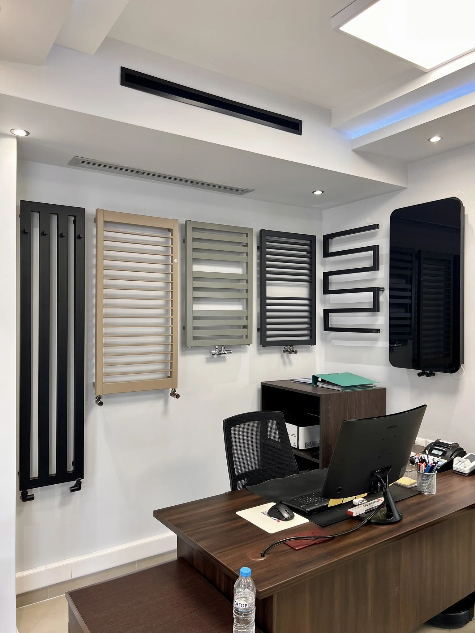 Interior view of the Tsolakidis showroom featuring a wide selection of modern decorative radiators, including vertical heating panels, mirror-style radiators, and colored designer units for both living spaces and bathrooms