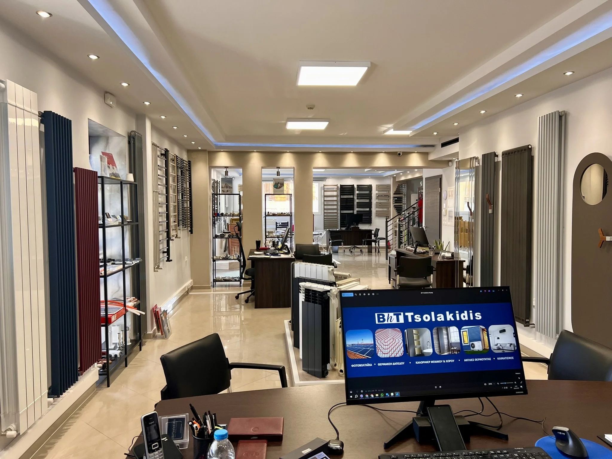 Interior view of the Tsolakidis showroom featuring a wide selection of modern decorative radiators, including vertical heating panels, mirror-style radiators, and colored designer units
