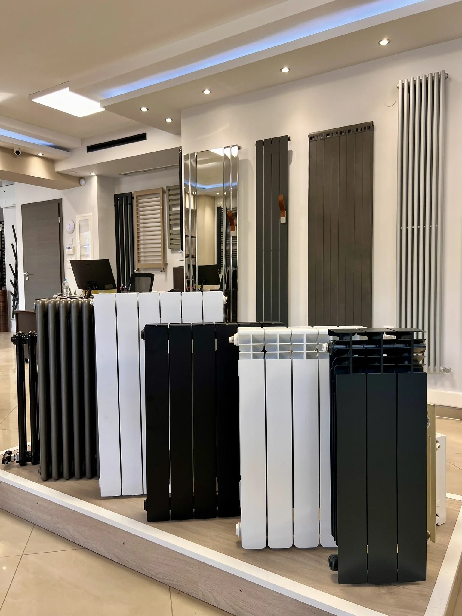 Interior view of the Tsolakidis showroom featuring a wide selection of modern decorative radiators, including vertical heating panels, mirror-style radiators, and colored designer units