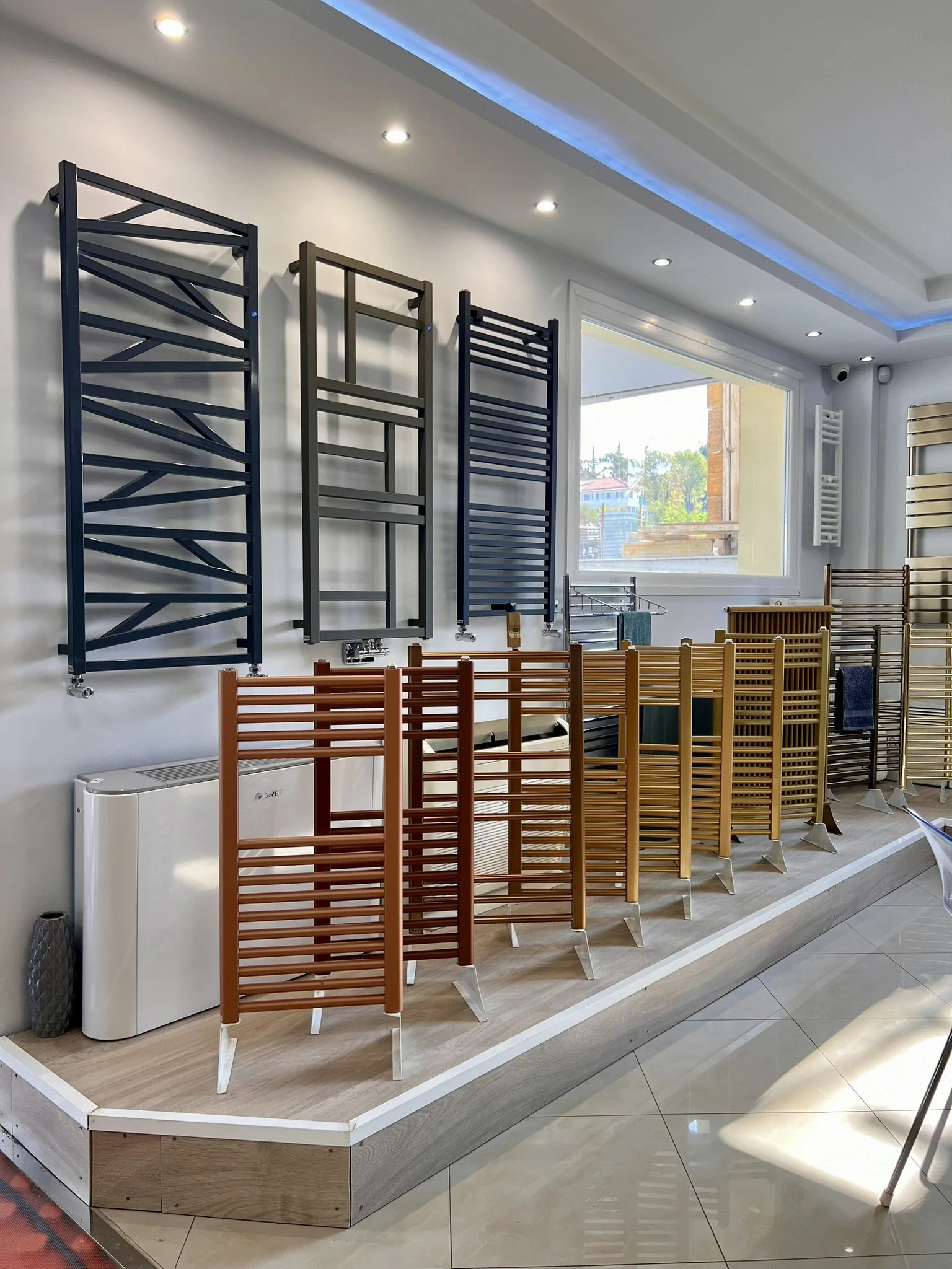 Interior view of the Tsolakidis showroom featuring a wide selection of modern decorative radiators, including vertical heating panels, mirror-style radiators, and colored designer units for both living spaces and bathrooms
