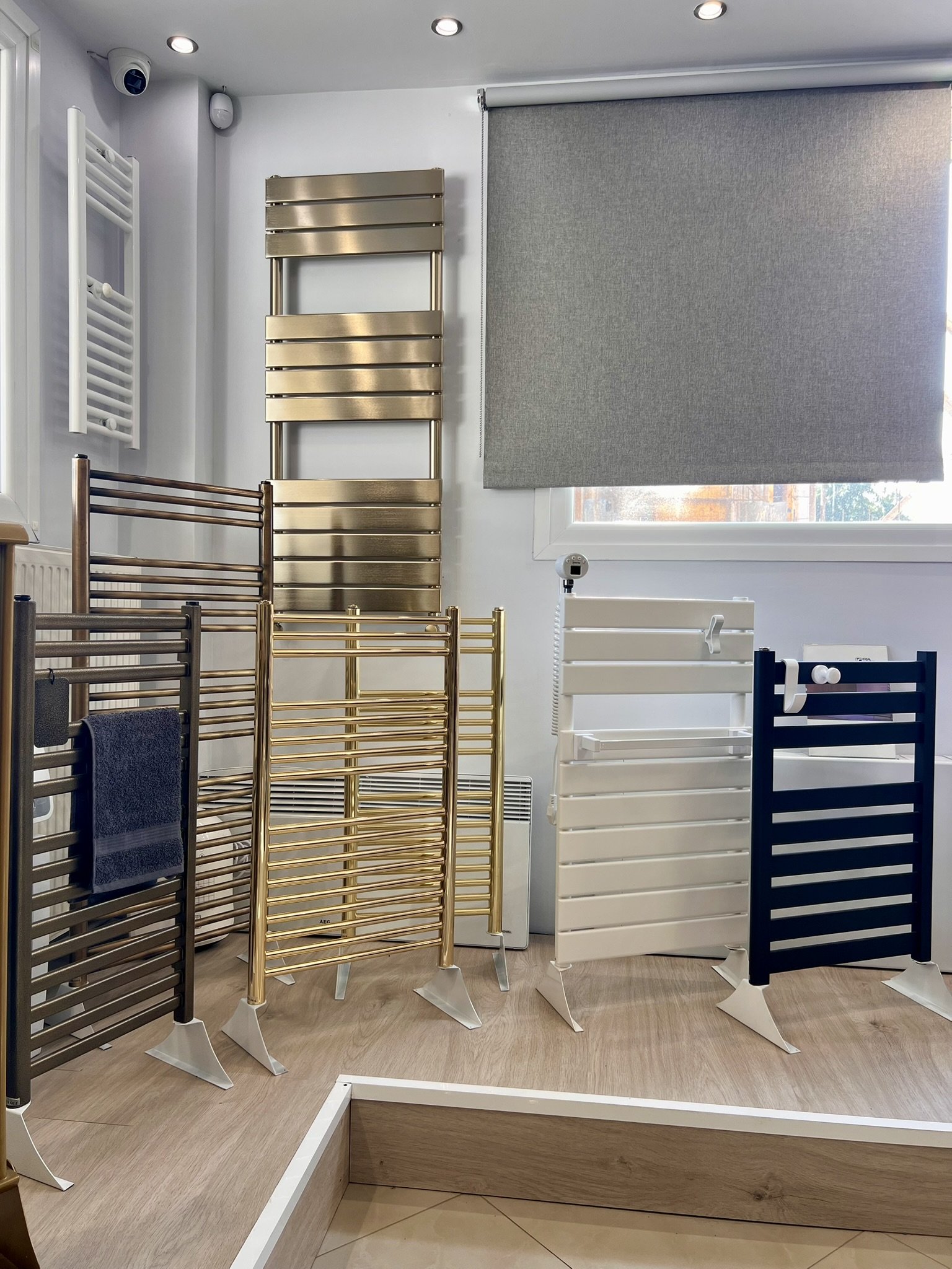 Interior view of the Tsolakidis showroom featuring a wide selection of modern decorative radiators, including vertical heating panels, mirror-style radiators, and colored designer units for both living spaces and bathrooms