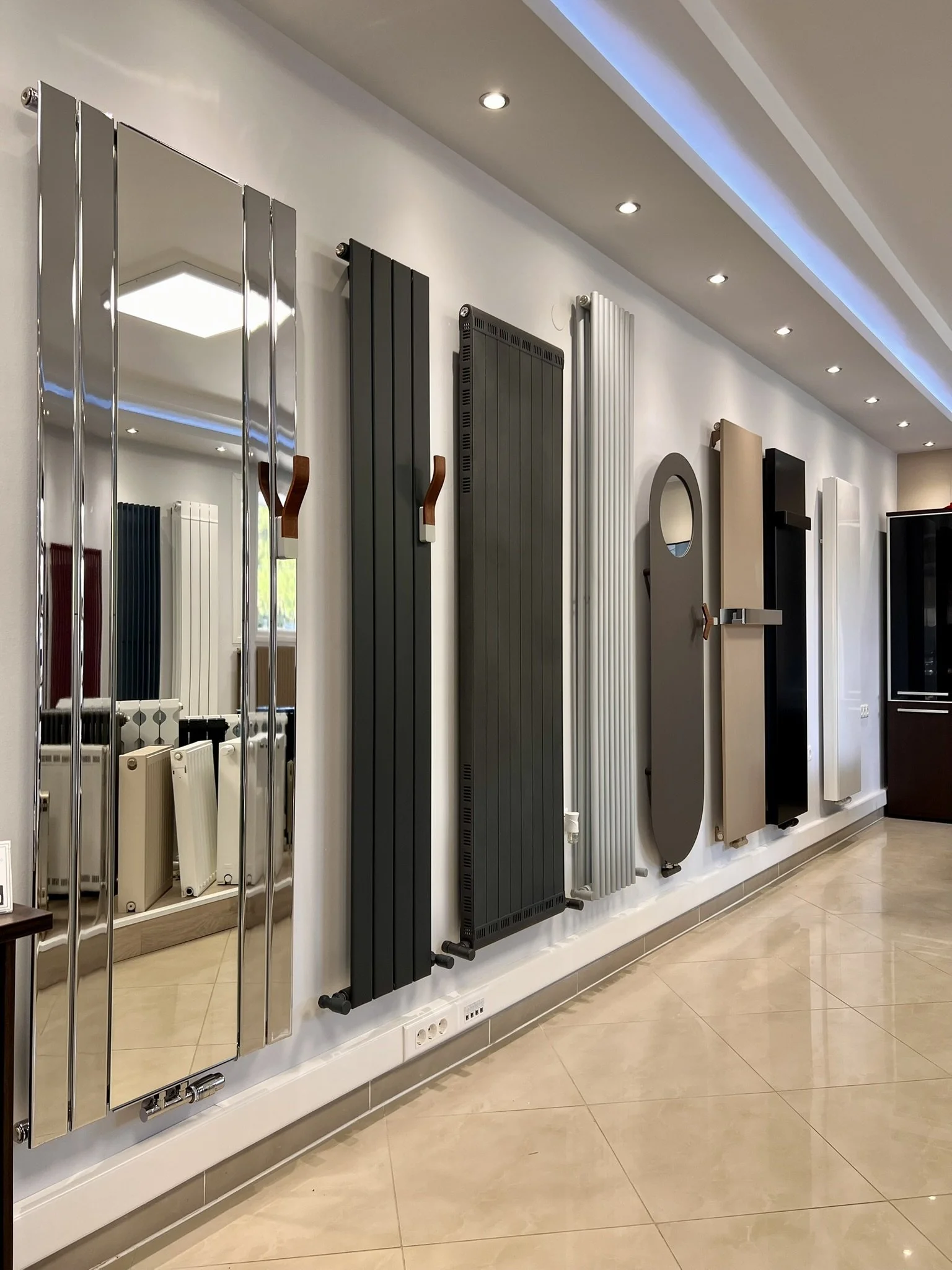 Interior view of the Tsolakidis showroom featuring a wide selection of modern decorative radiators, including vertical heating panels, mirror-style radiators, and colored designer units