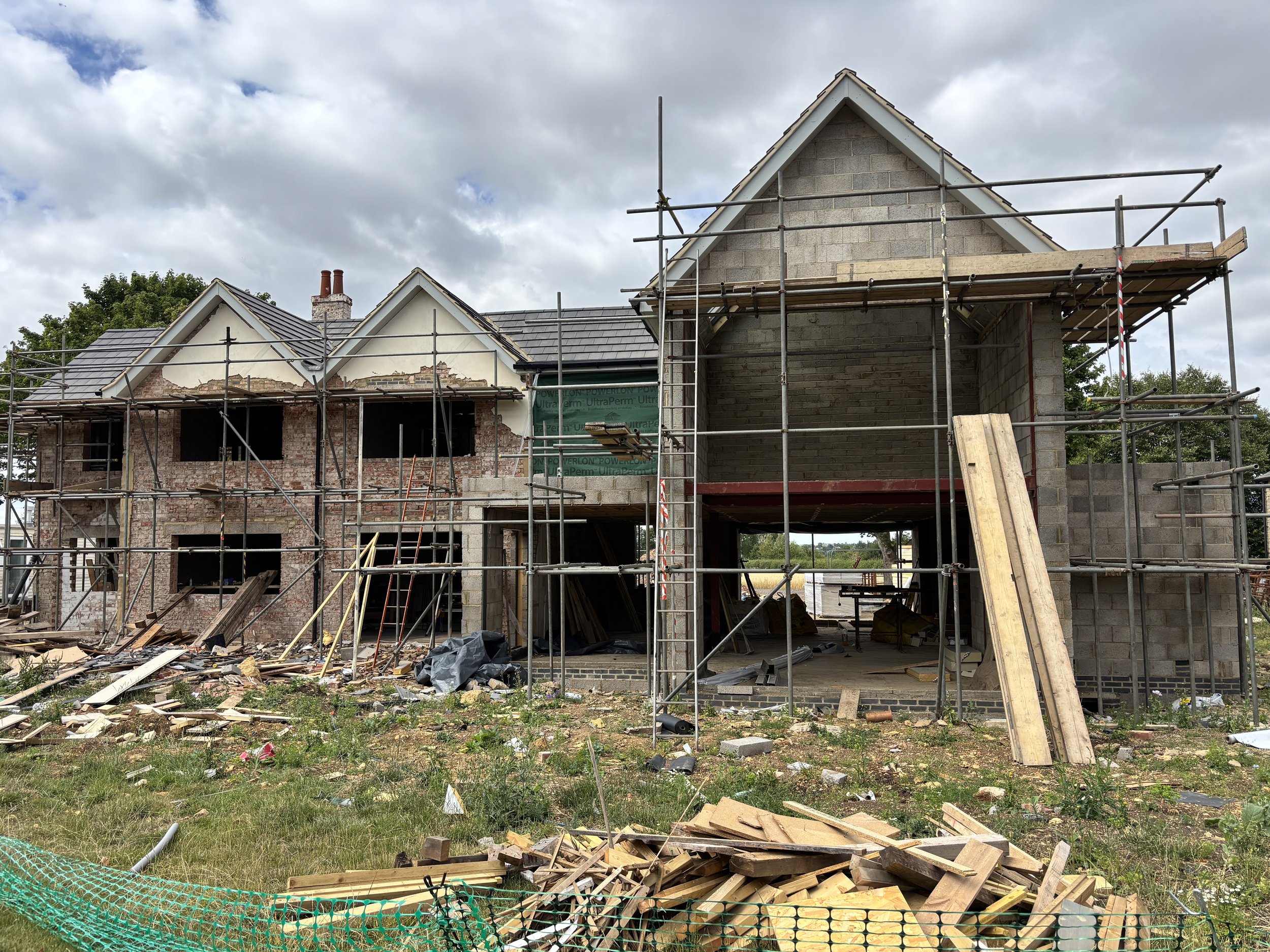 Under construction house with scaffolding and building materials scattered on the ground.