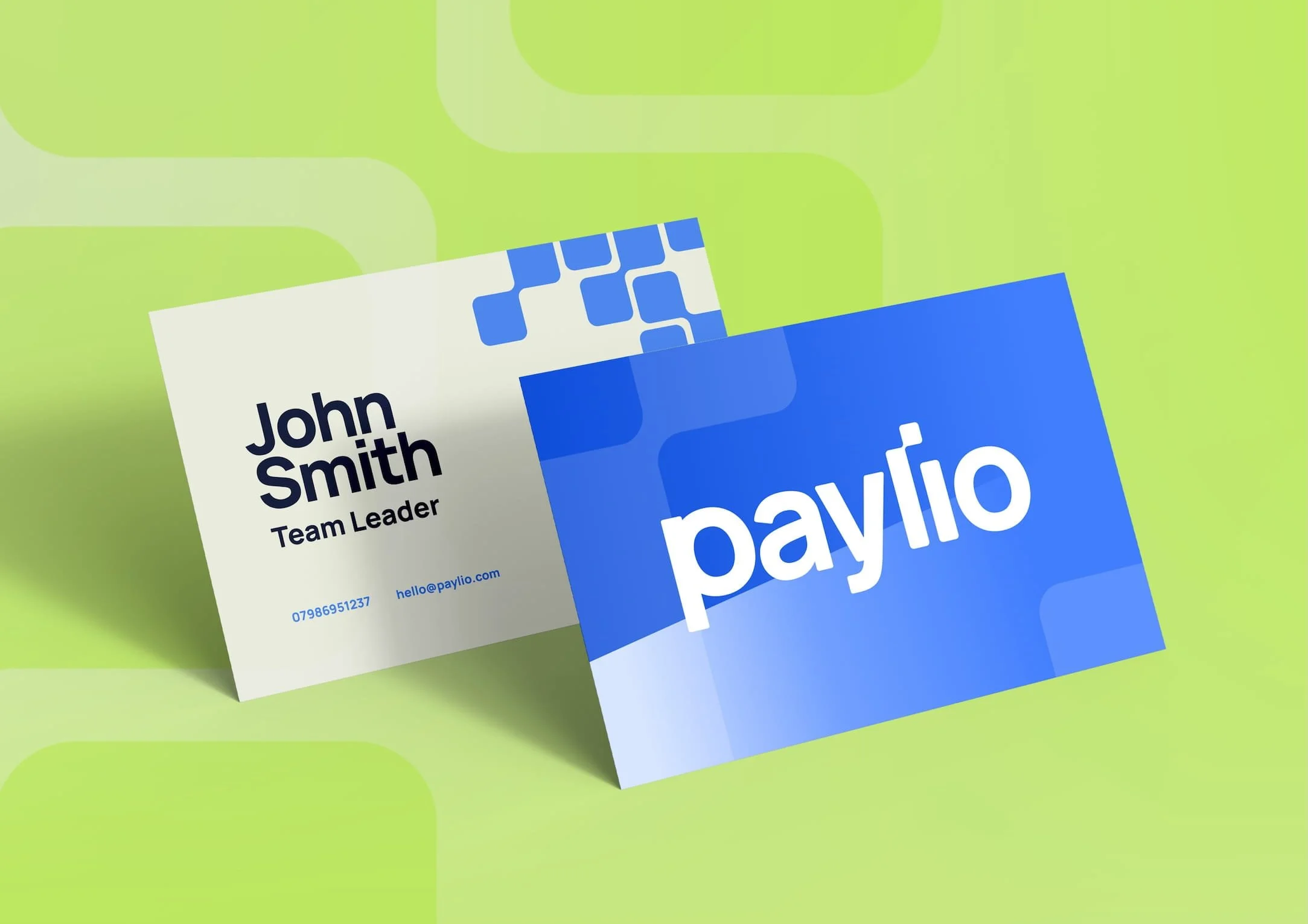 Business cards from Paylio with green, blue, and white design, featuring names and contact information, placed against a light green background. Design by Hubble.