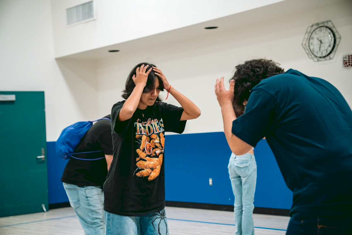 Girl with hands on her head and distressed expression, adult man also distressed, in a gymnasium.