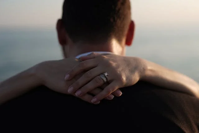 woman's arm around her fiance with engagement ring