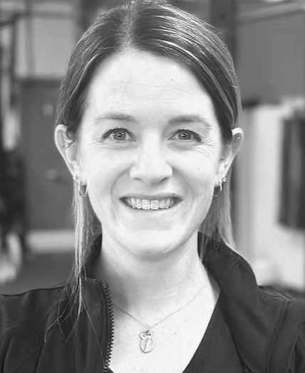 Black and white portrait of a smiling woman with short dark hair and a beard, wearing a collared shirt.