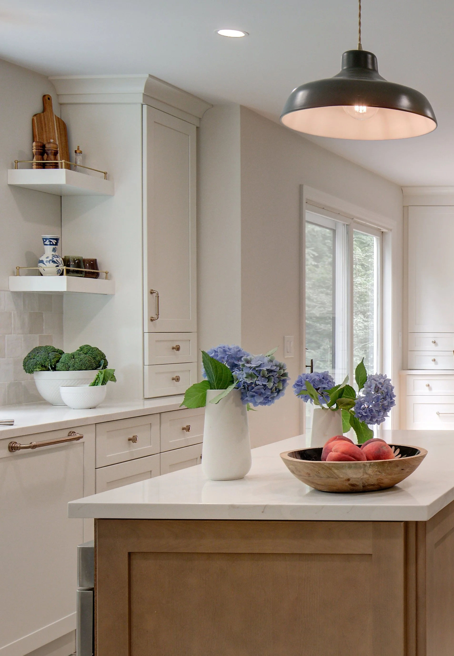 Blue flowers in white vase on kitchen island counter.