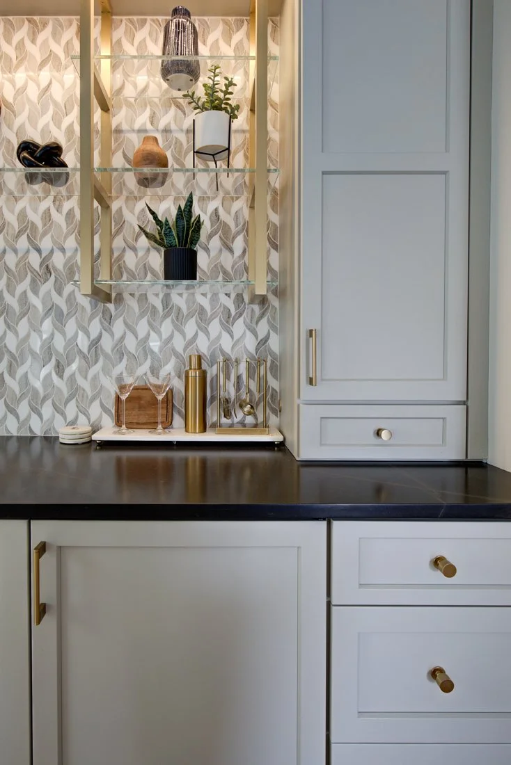 Modern home bar with glass shelves and patterned backsplash.