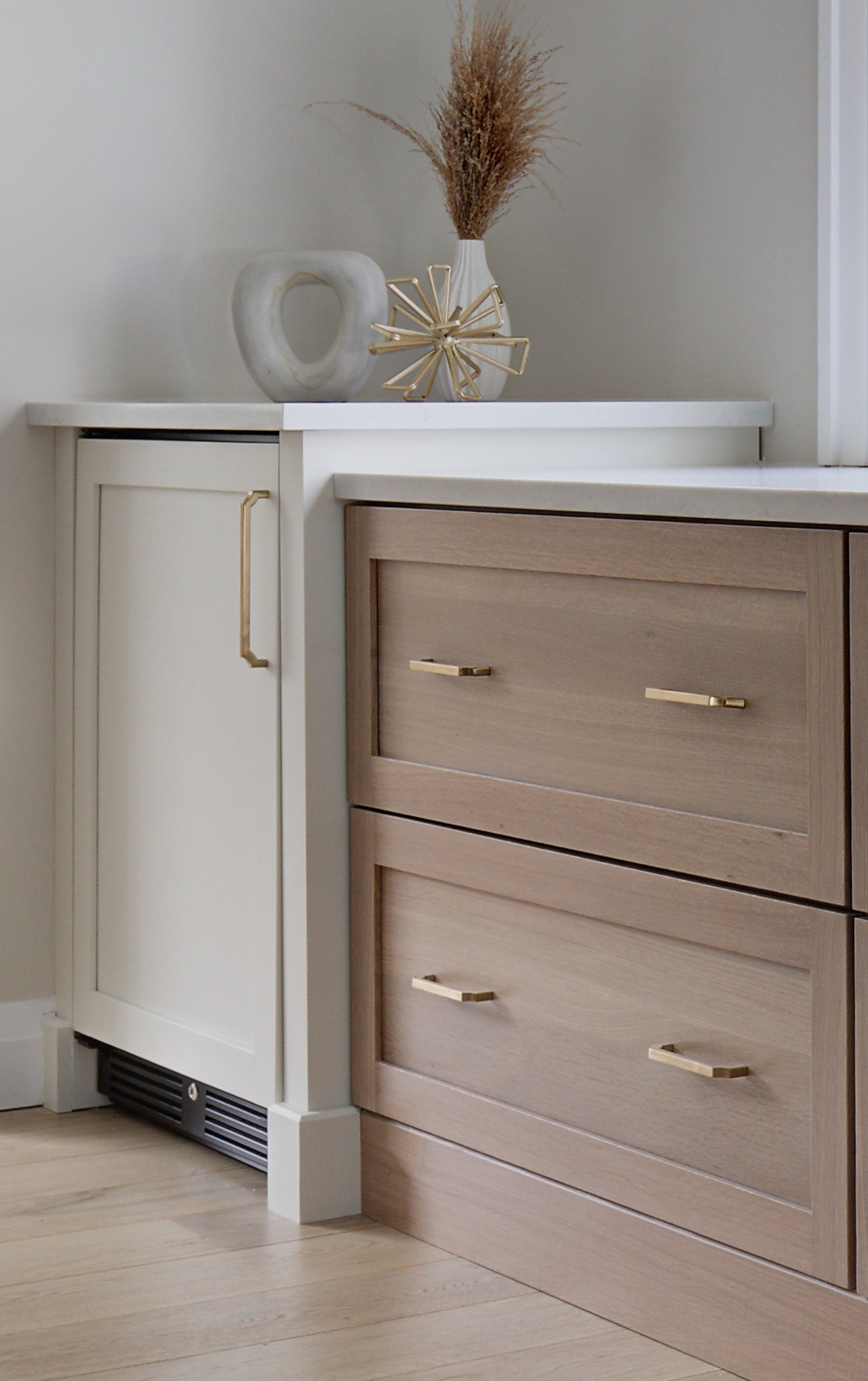 Neutral kitchen cabinets with gold handles and decorative vases.