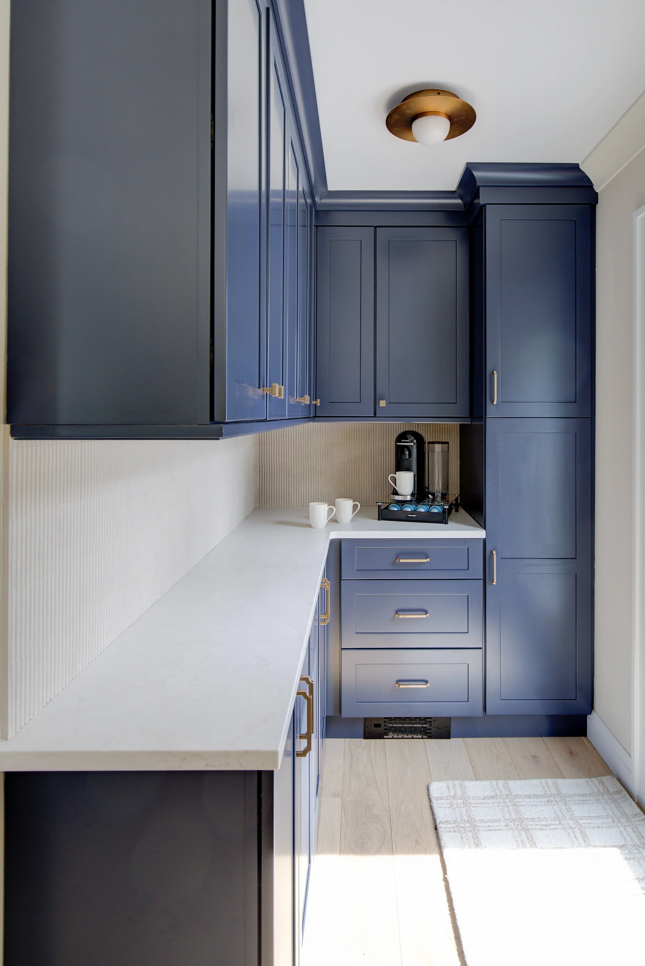 Modern blue kitchen cabinets with white marble countertops.