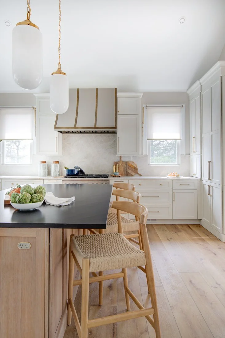 Modern kitchen with wood island, woven stools, and white cabinetry.