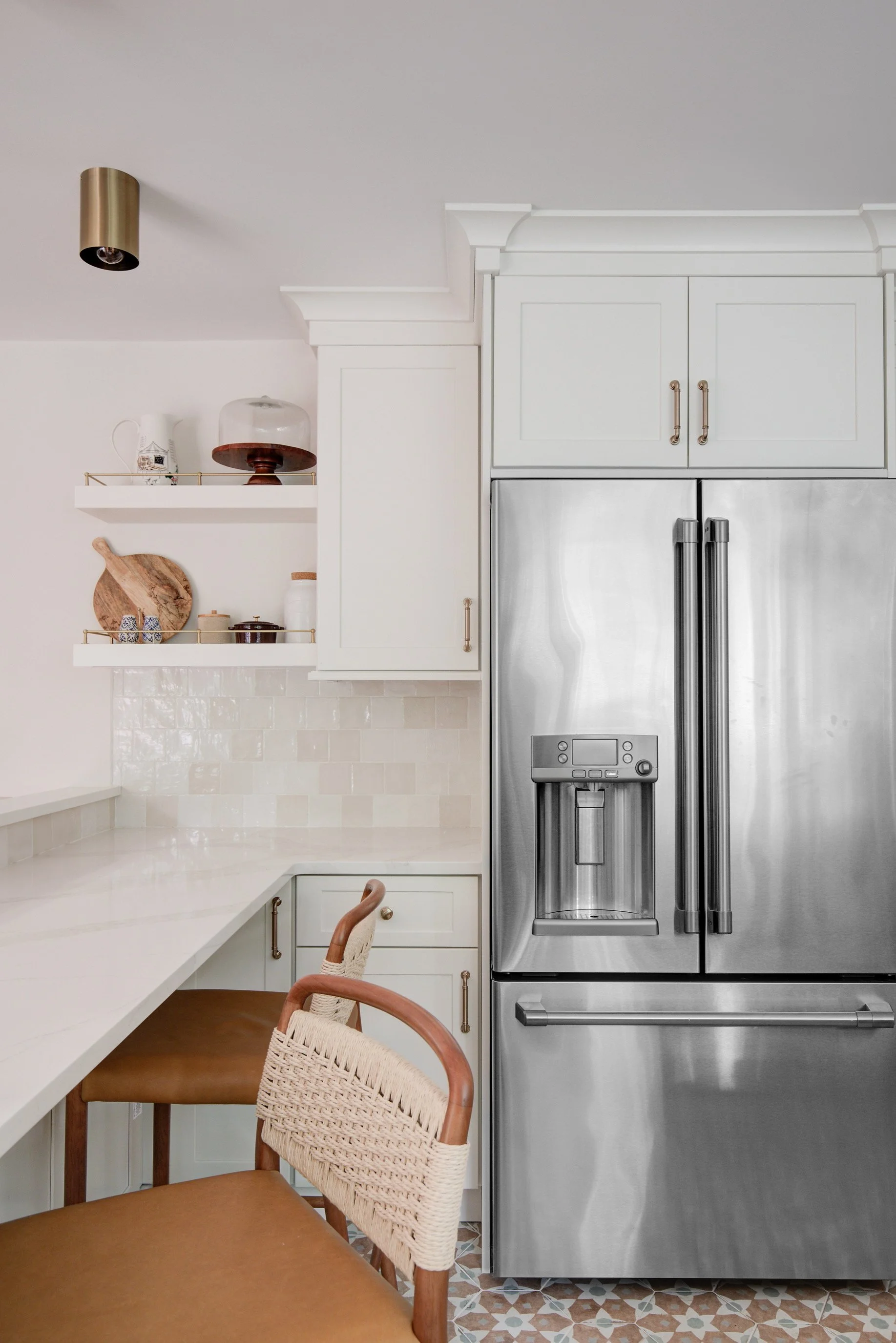 Stainless steel refrigerator beside counter with wooden barstools.