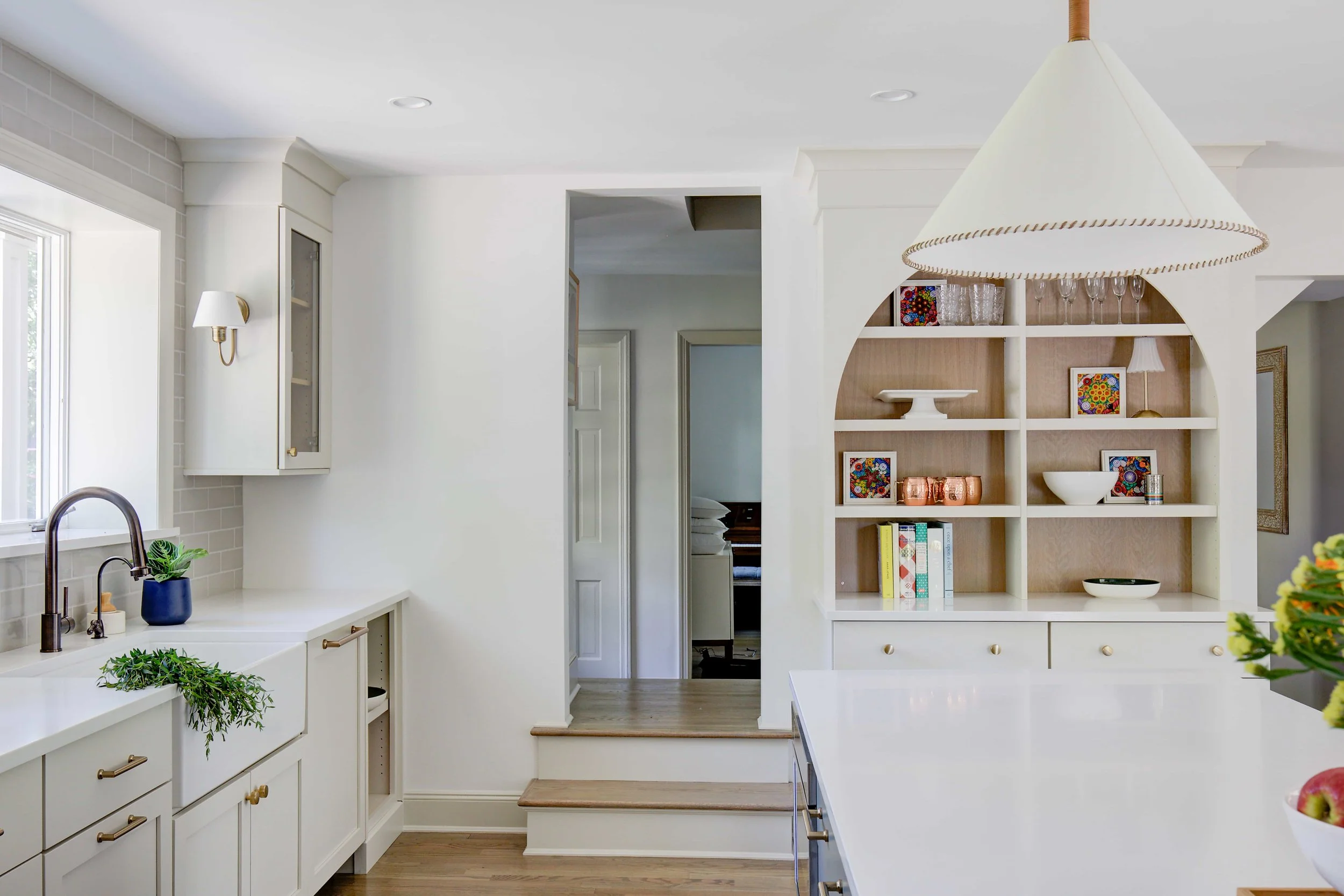 Modern white kitchen with arched shelving and island counter.
