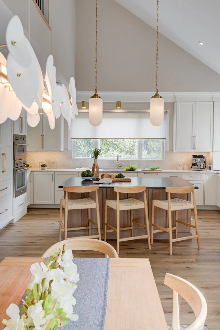 Open kitchen with wood island, woven stools, and pendant lights.