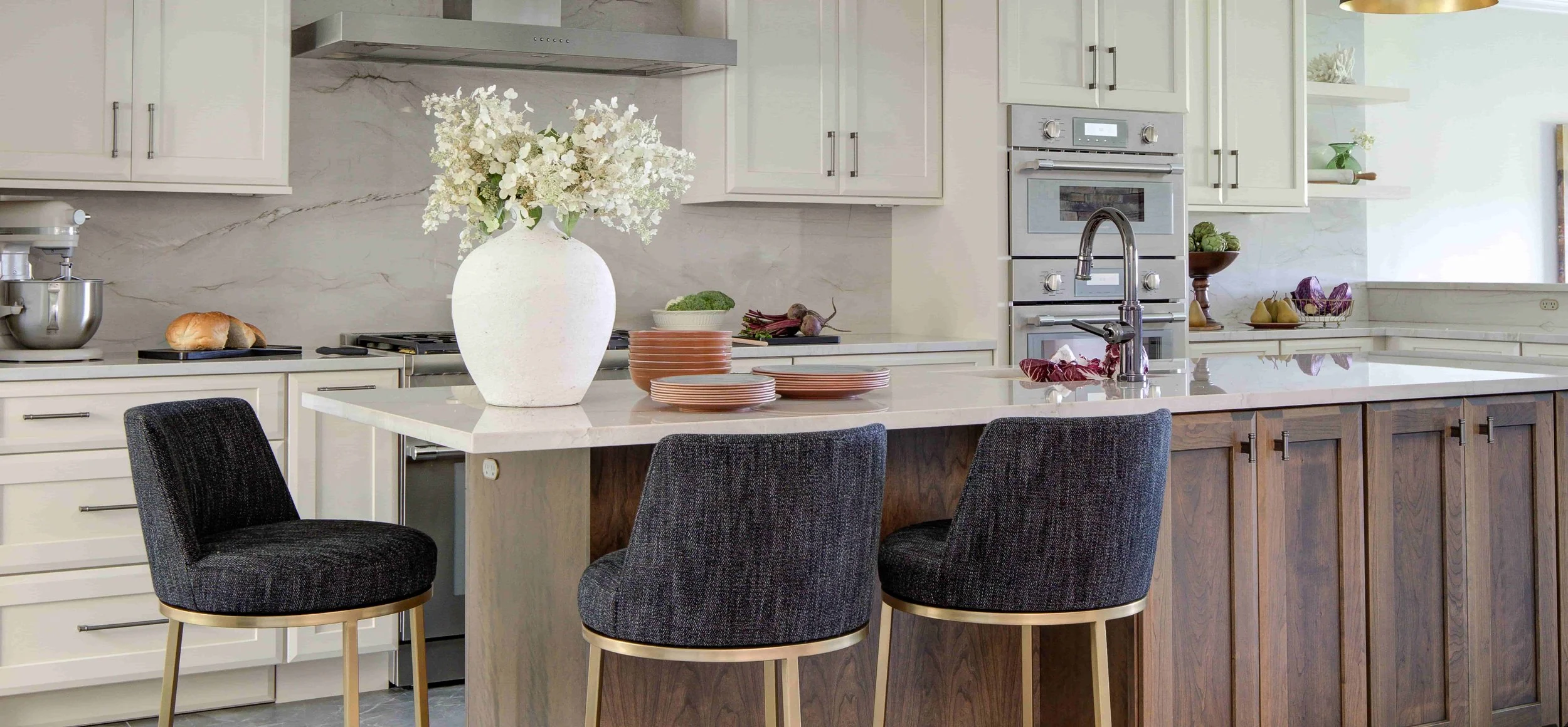 Kitchen island with three chairs and flower vase.