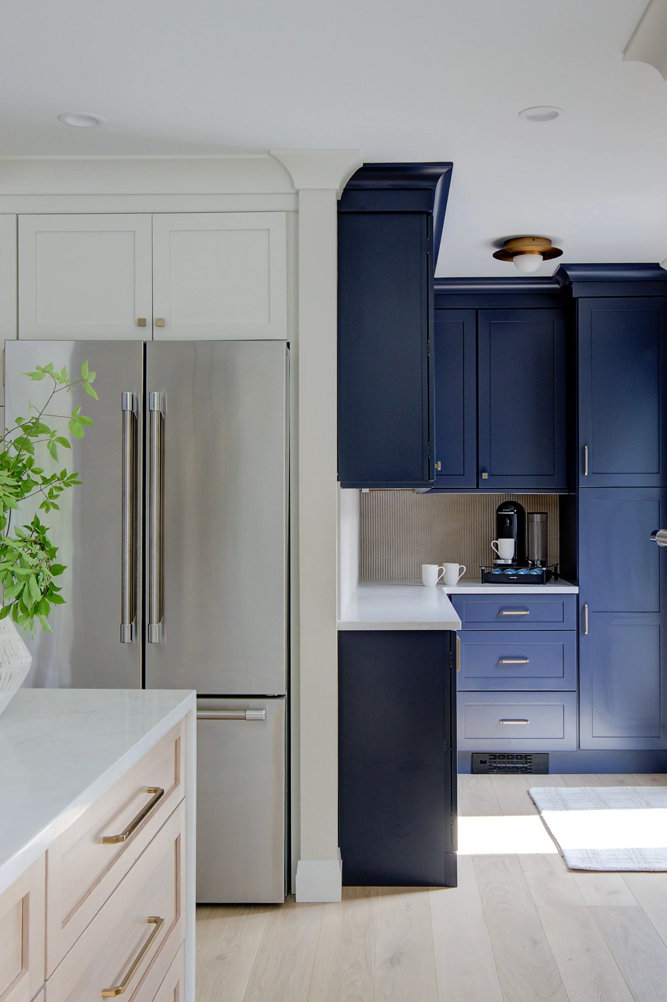 Blue kitchen cabinets next to a stainless steel refrigerator.