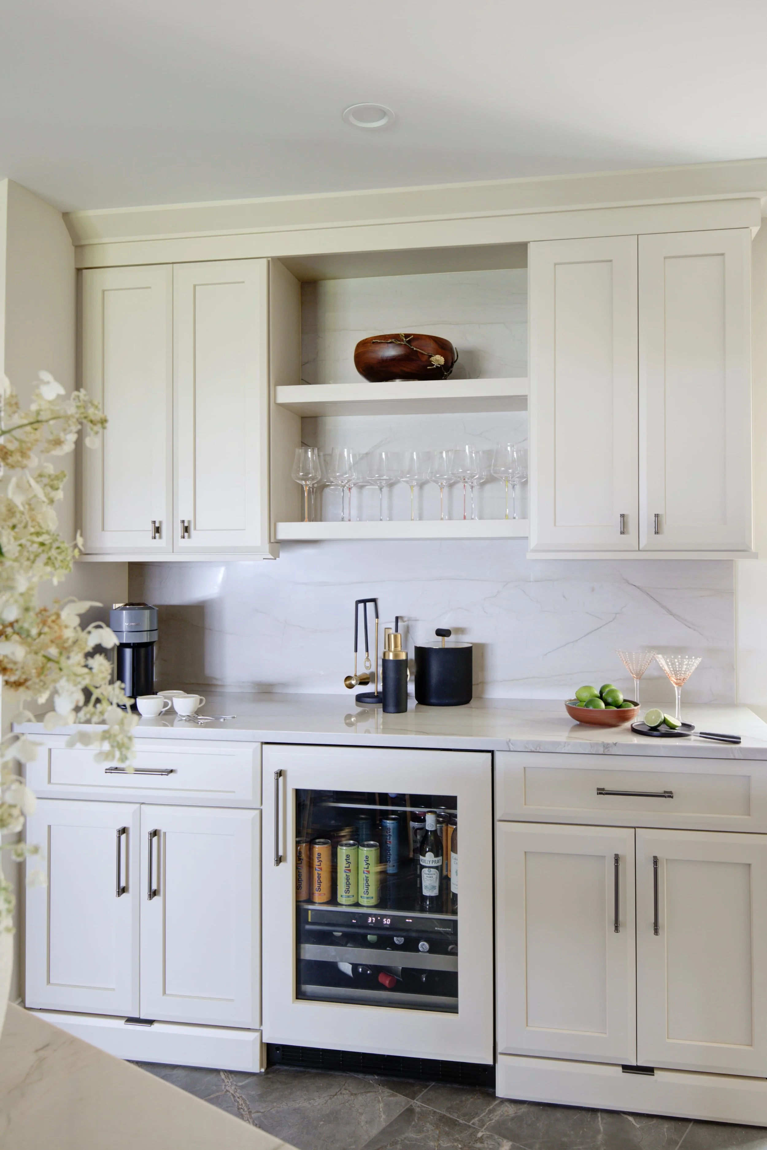 White kitchen bar with built-in beverage cooler and shelving.