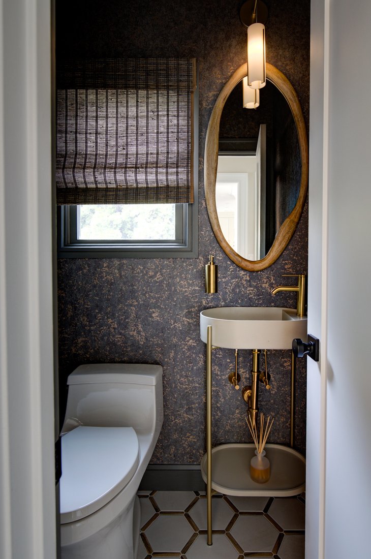 Modern powder room with gold accents and textured wallpaper.