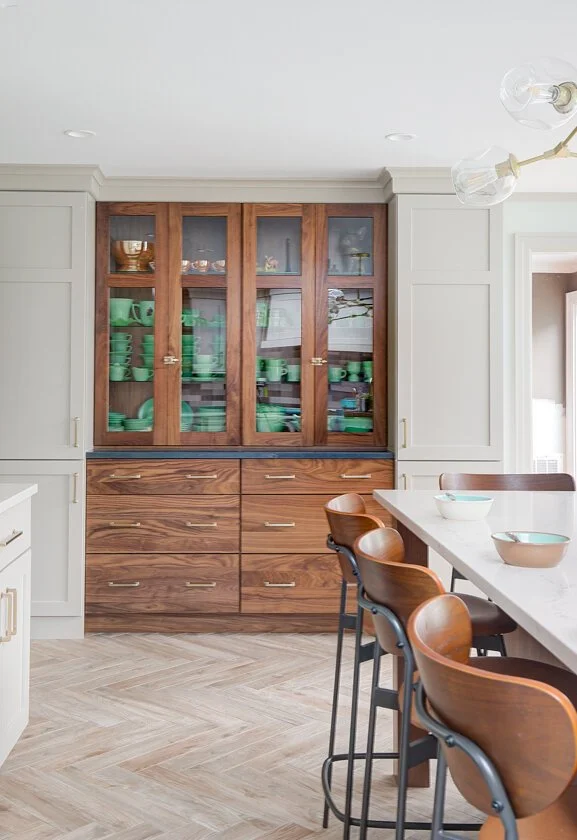 Wood hutch with green glassware and herringbone tile floor.