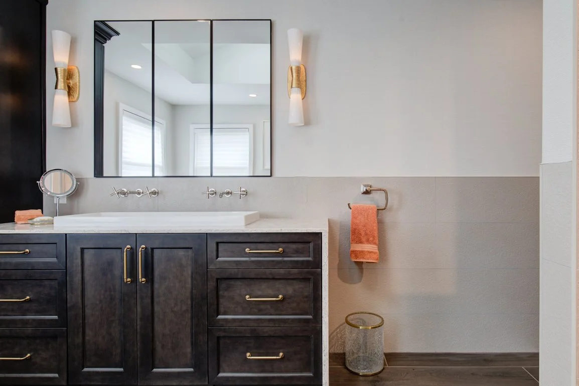 Dark wood bathroom vanity with white sink and sconces.