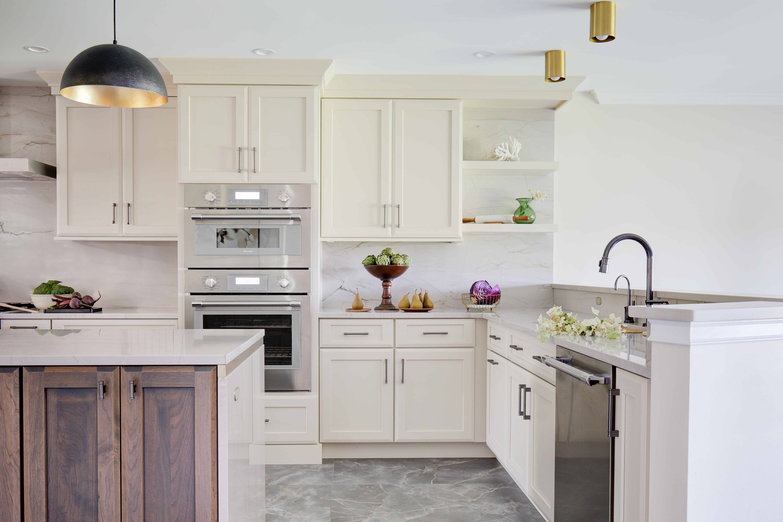 White kitchen with double ovens and stainless steel sink.
