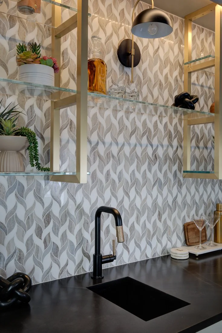 Wet bar sink with black faucet and wave patterned tile.
