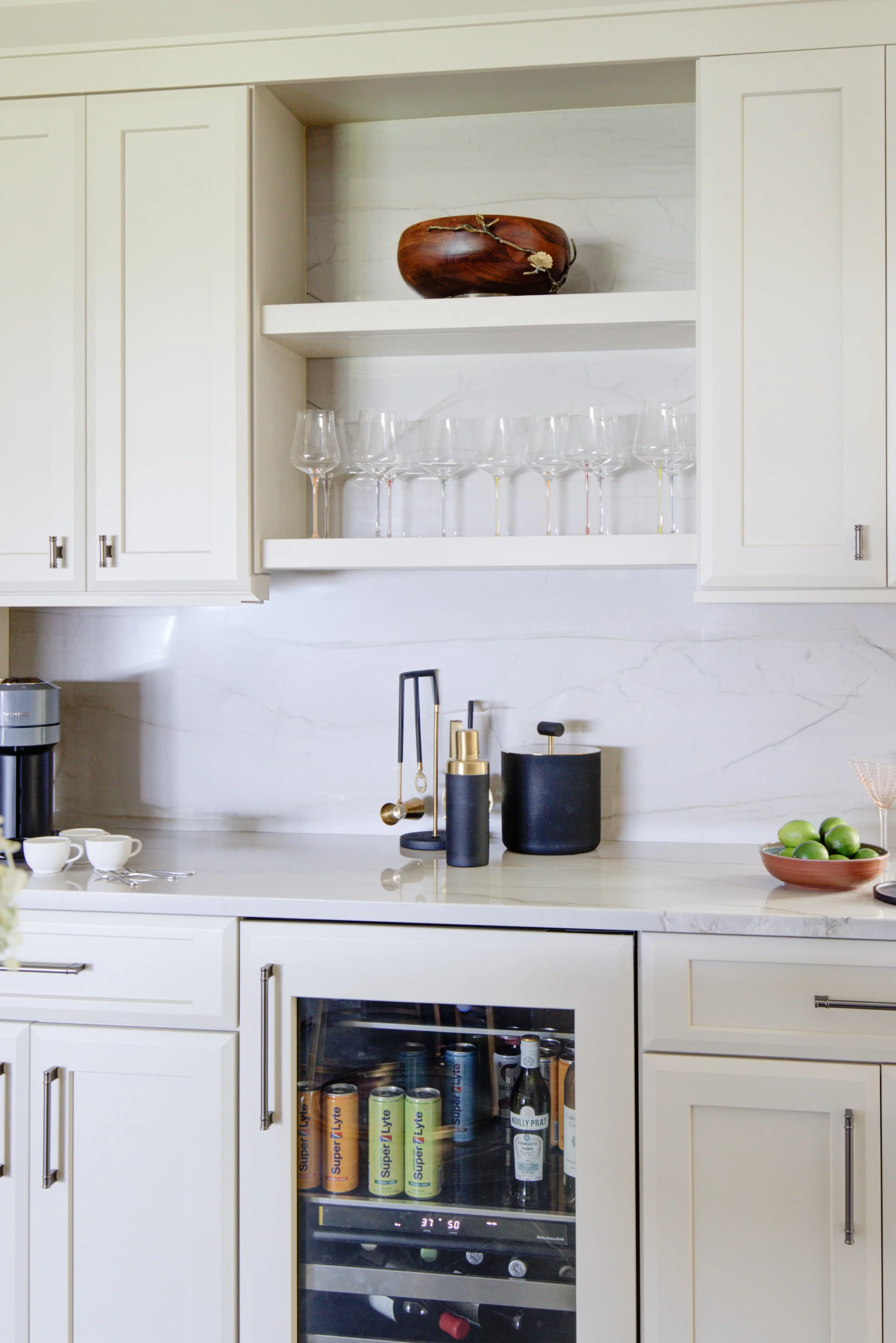 White kitchen bar with built-in beverage cooler and glassware.