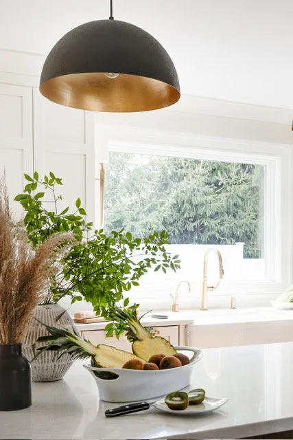 Kitchen island with fruit bowl under a black pendant light.