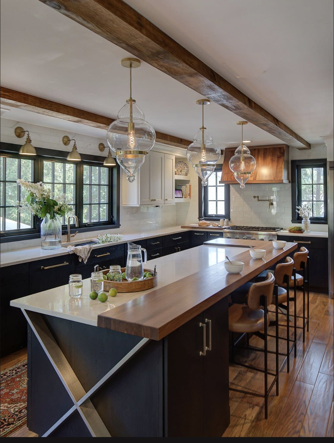 Modern kitchen with black cabinets and wood ceiling beams.