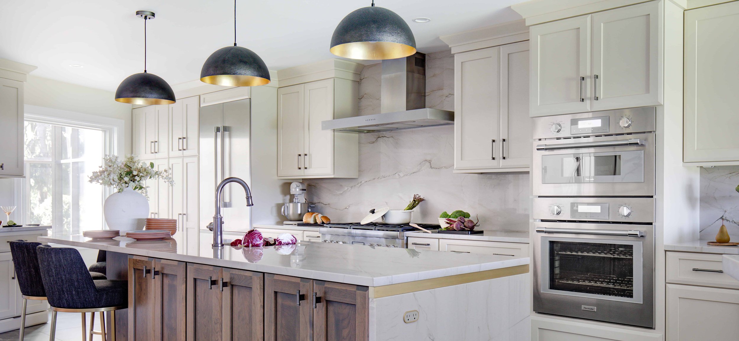 Modern kitchen with island, wooden cabinets, and pendant lights.