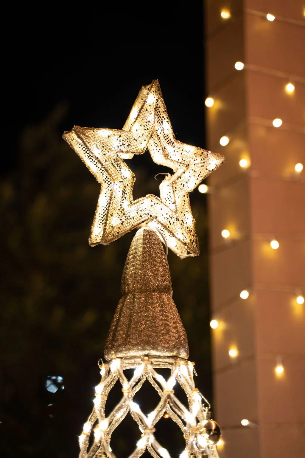 Editorial close-up of illuminated holiday décor featuring a star tree topper and warm white string lights installed at Fleming’s Prime Steakhouse in Tampa