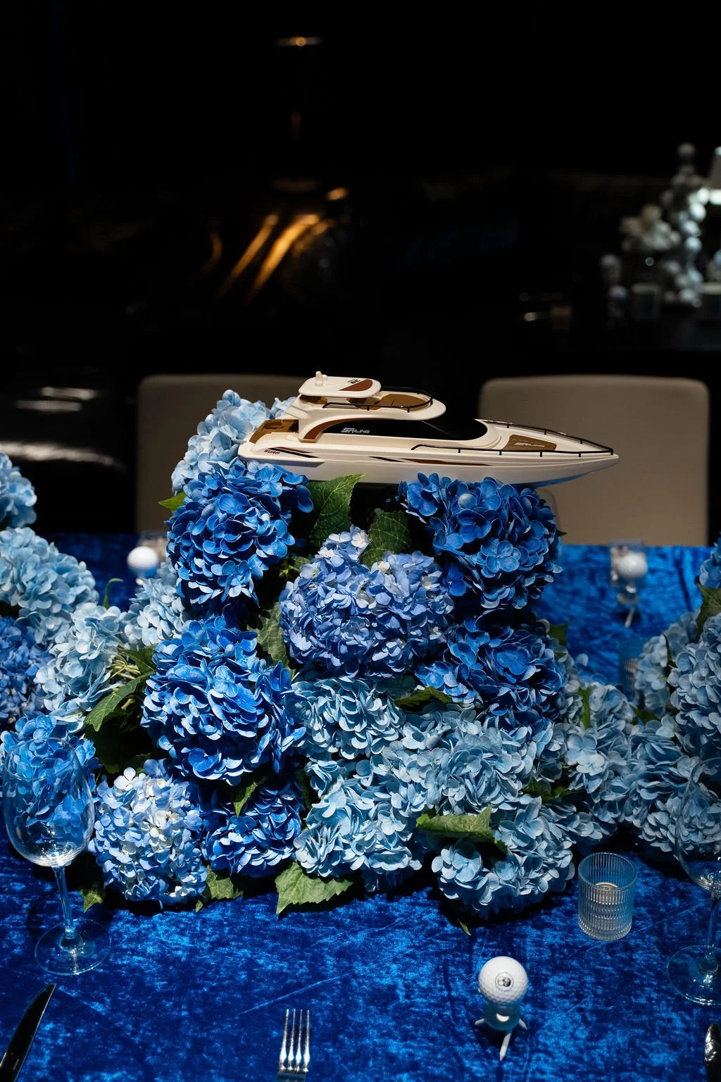 Editorial detail shot of a yacht-themed floral centerpiece featuring blue hydrangeas and sculptural styling for a luxury event tablescape