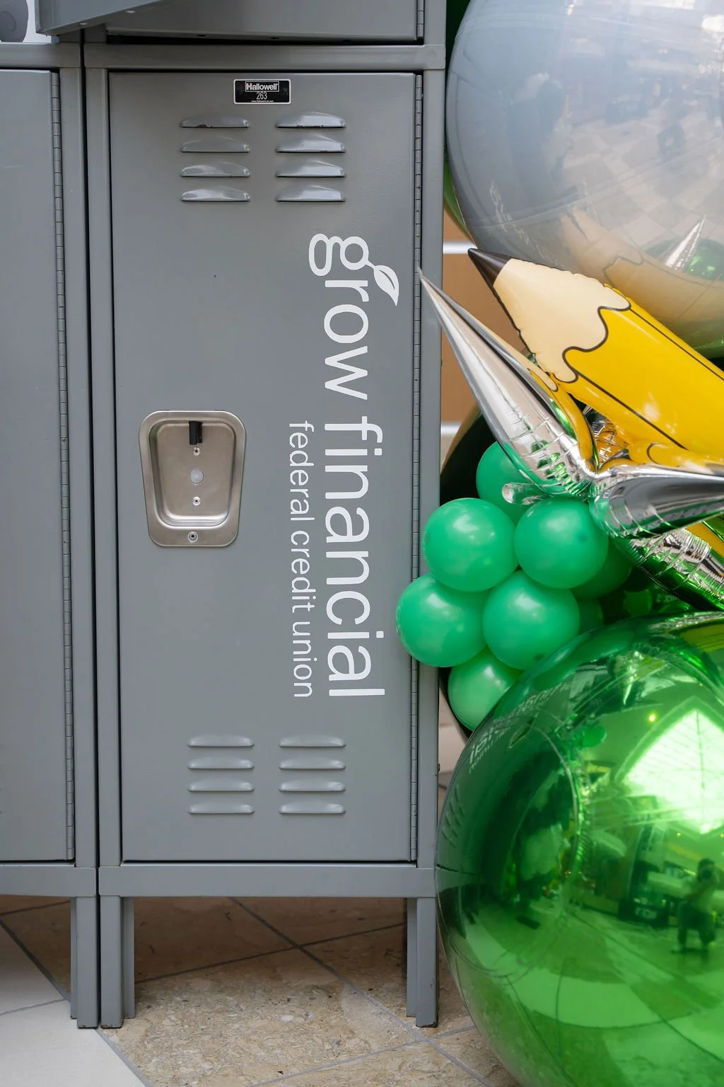 Editorial detail image of a Grow Financial Federal Credit Union–branded locker installation styled with green balloon décor for a Back to School event activation