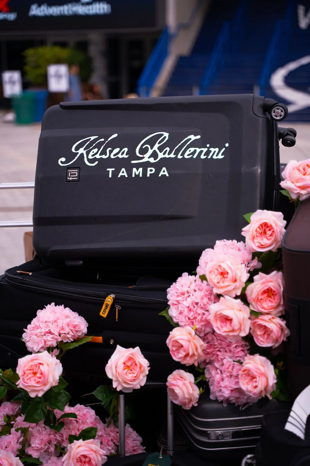Fan photo op display for the Kelsea Ballerini concert featuring branded luggage props and pink floral décor at a live music event