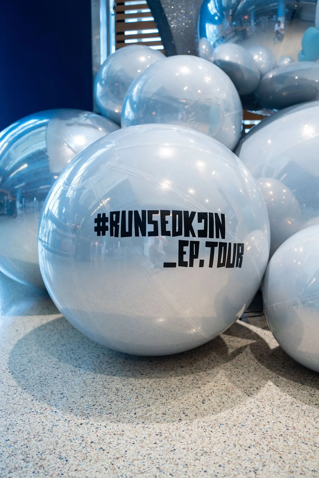 Editorial image of custom white mirror ball balloon installations printed with ‘#RUNSEOKJIN_EP_TOUR,’ created for K-pop star Jin’s concert in Tampa