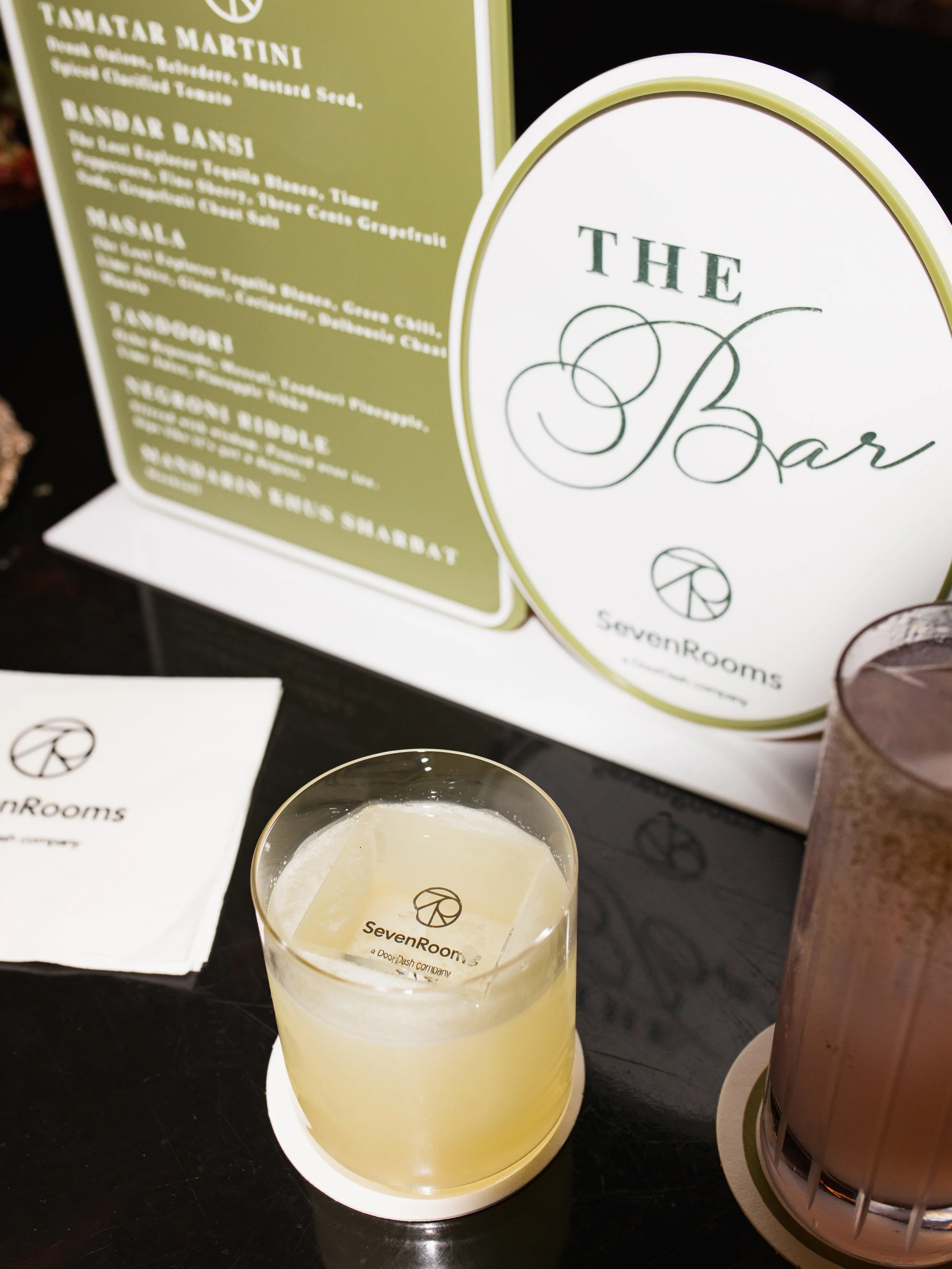Branded cocktail display featuring SevenRooms glassware and custom bar signage at a private party in London, England, UK