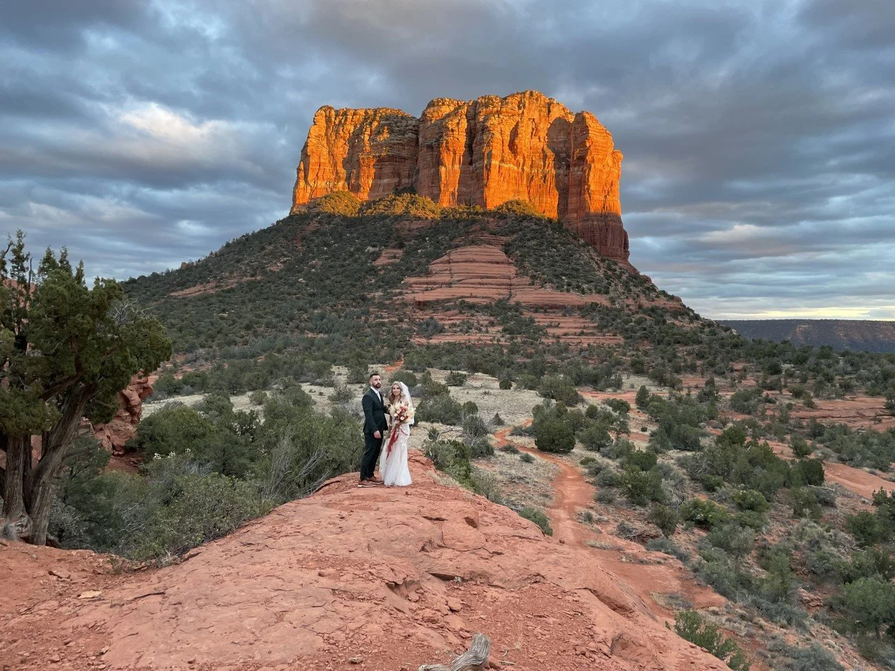 Earth Elopement wedding couple under dramatic sky with sunset lighting of Courthouse rock in the background