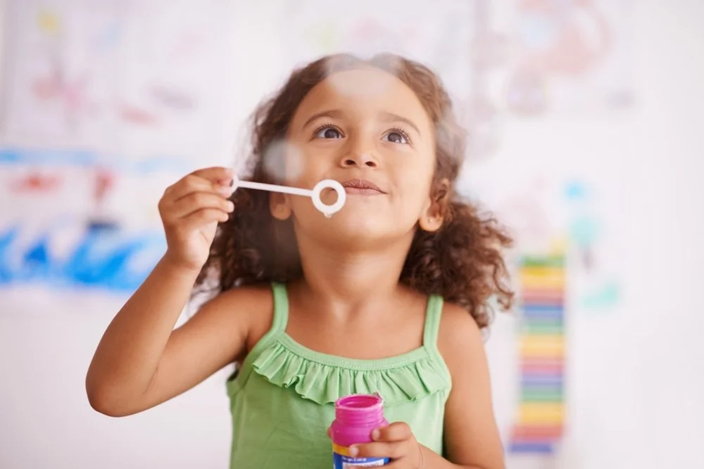 Young child blows bubbles