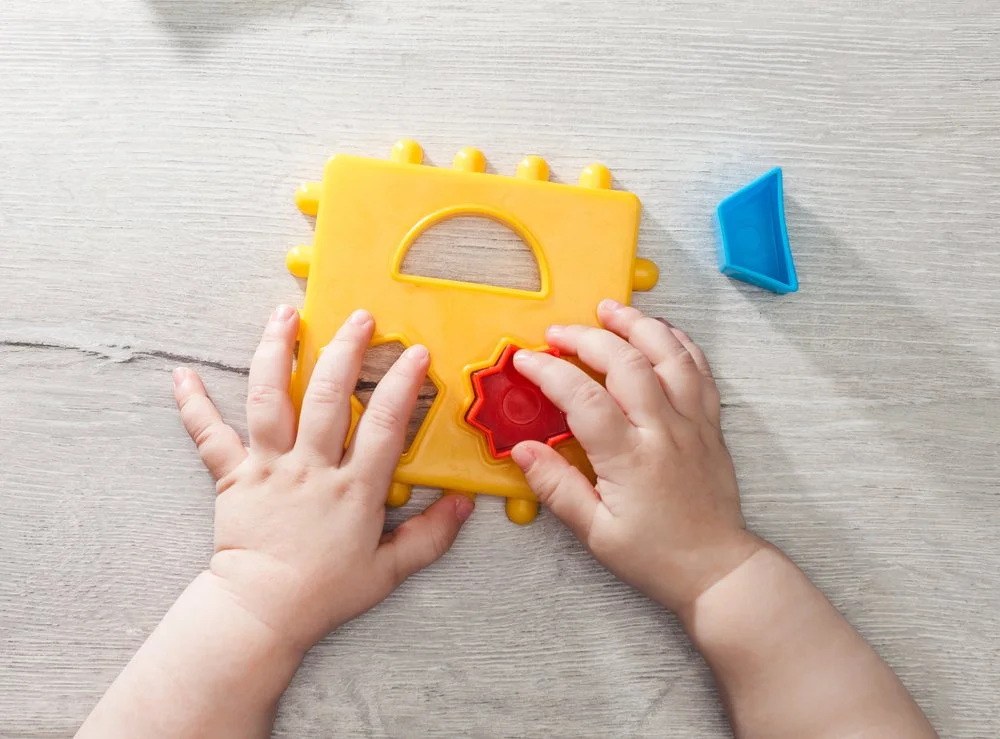 Closeup of a baby's hands arranging toys.