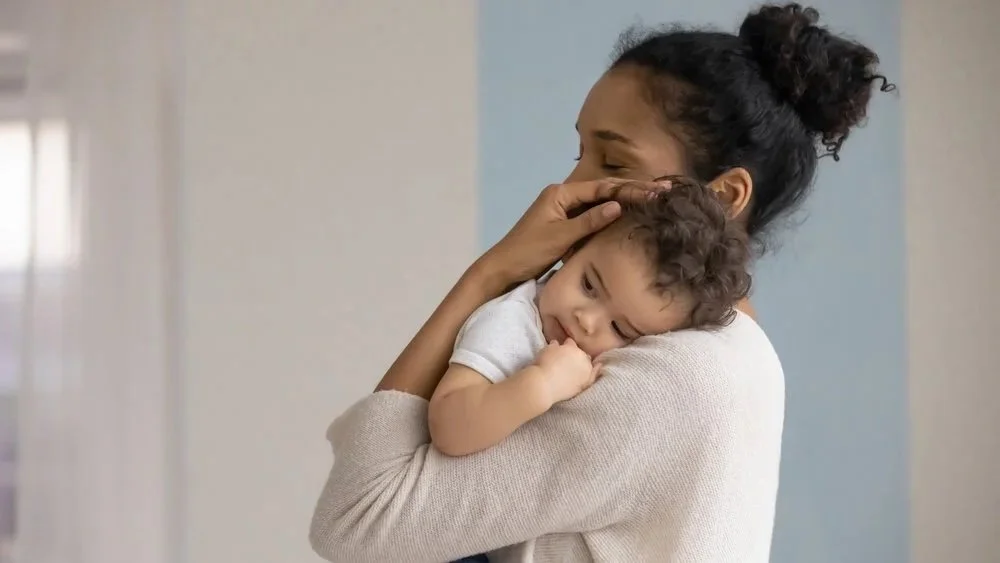 Mother supporting her baby's head on her shoulder