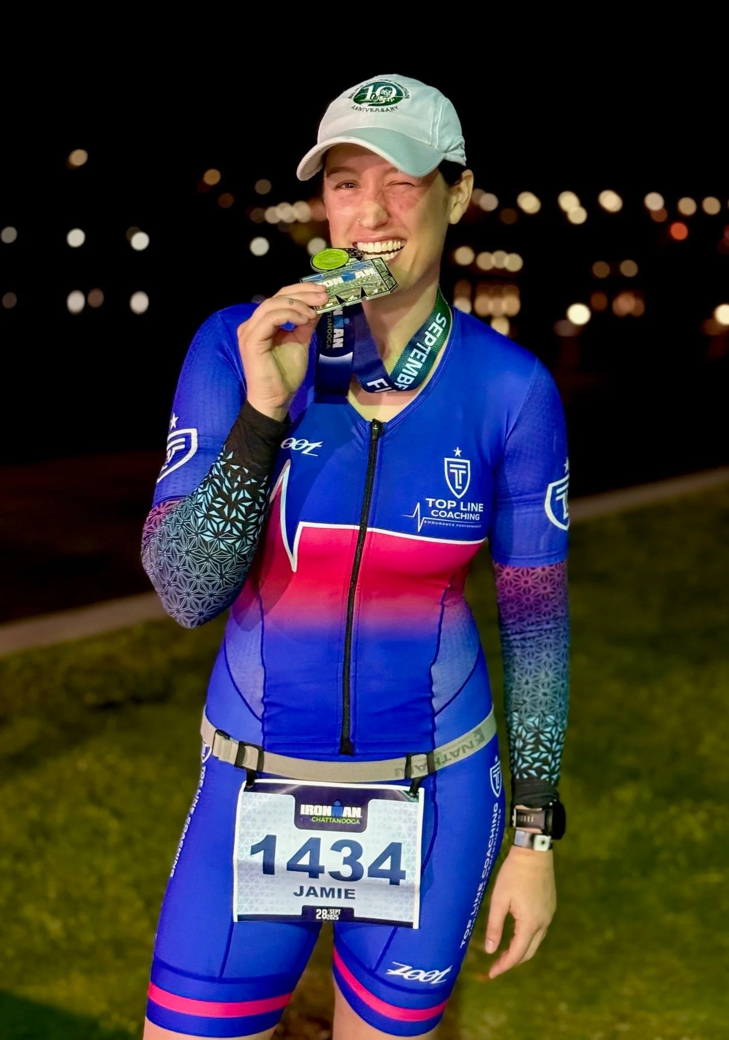 Jamie bites her finisher medal directly after finishing the full Ironman race