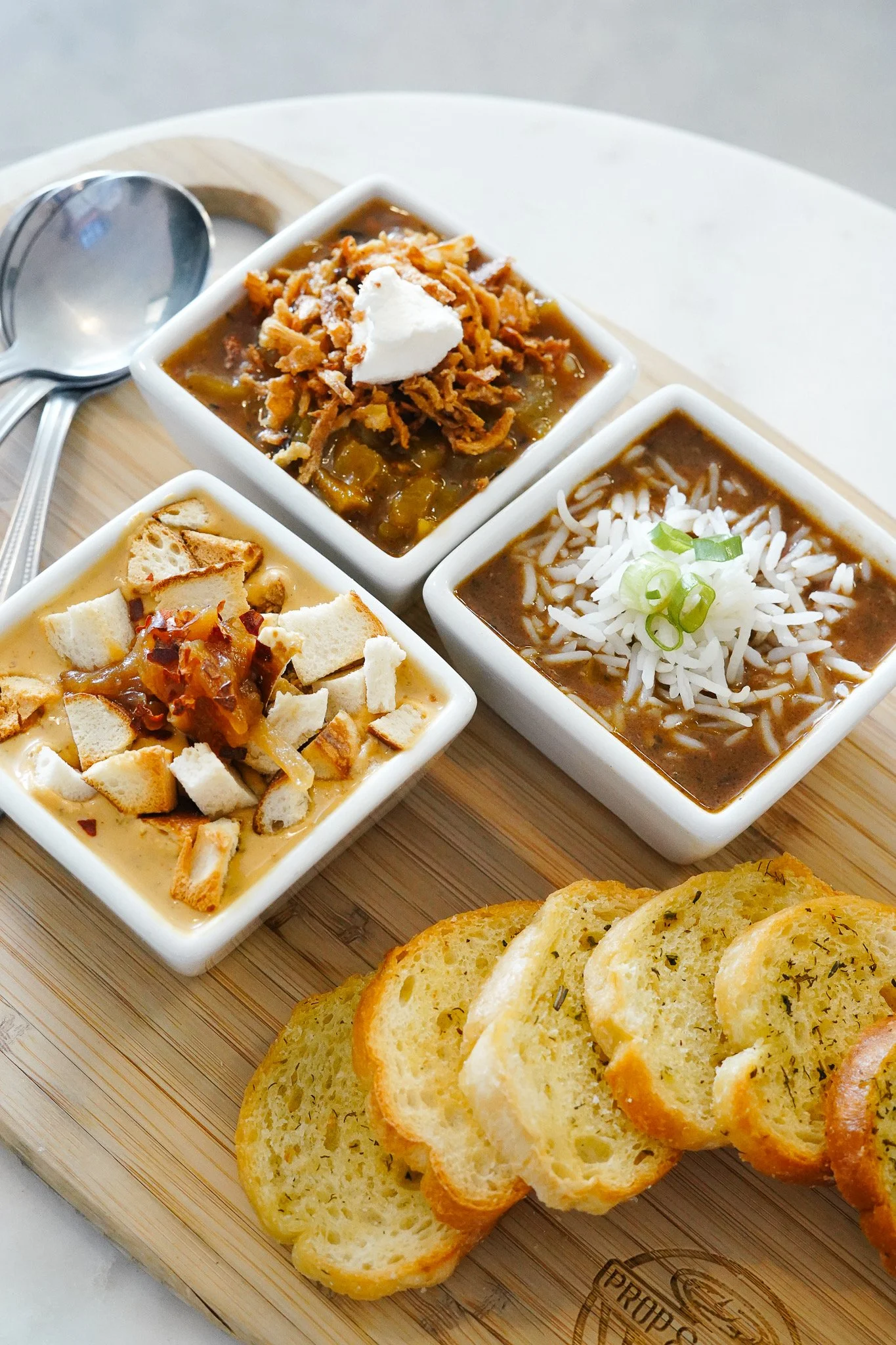 (3) Assortment of soup; Beer Cheese, Hatch Green Chilli, and Louisiana Style Gumbo with baked bread on the side