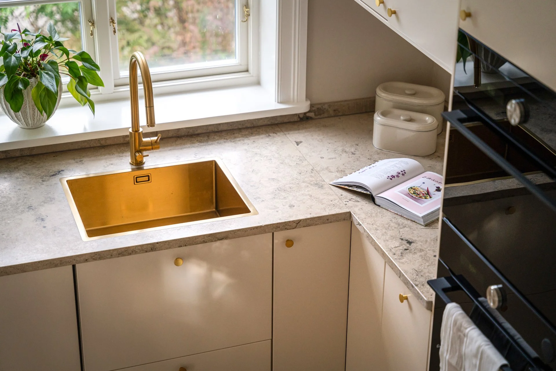 A clean kitchen counter made of stone materials with a brass sink.