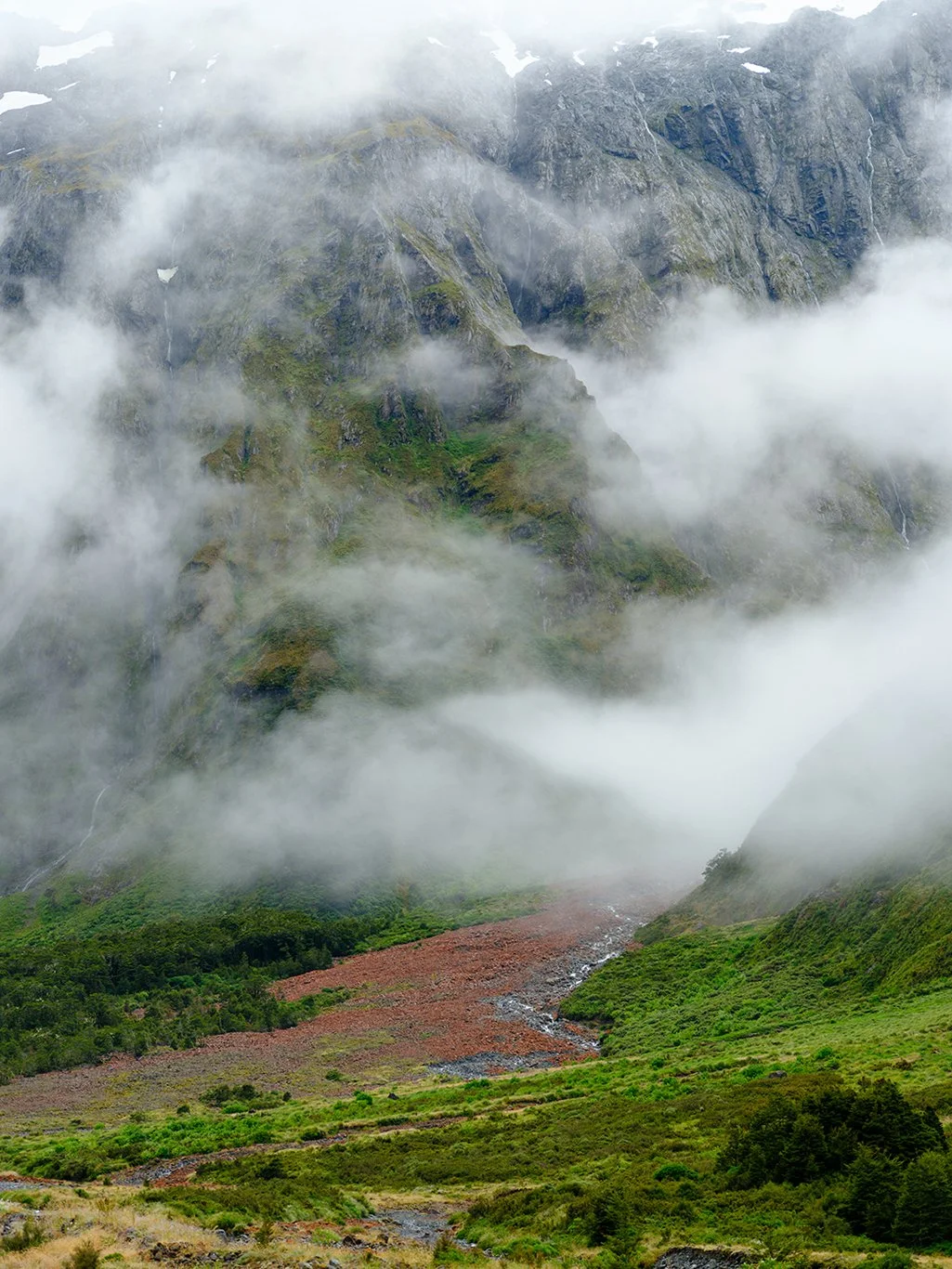 Fiordland National park has so many beautiful locations within its boundaries. I really loved the contrast on this location. The lush green trees, bushes and grasses split by the red of the rocks. The rocks are red like the sandstone in Moab or Zion