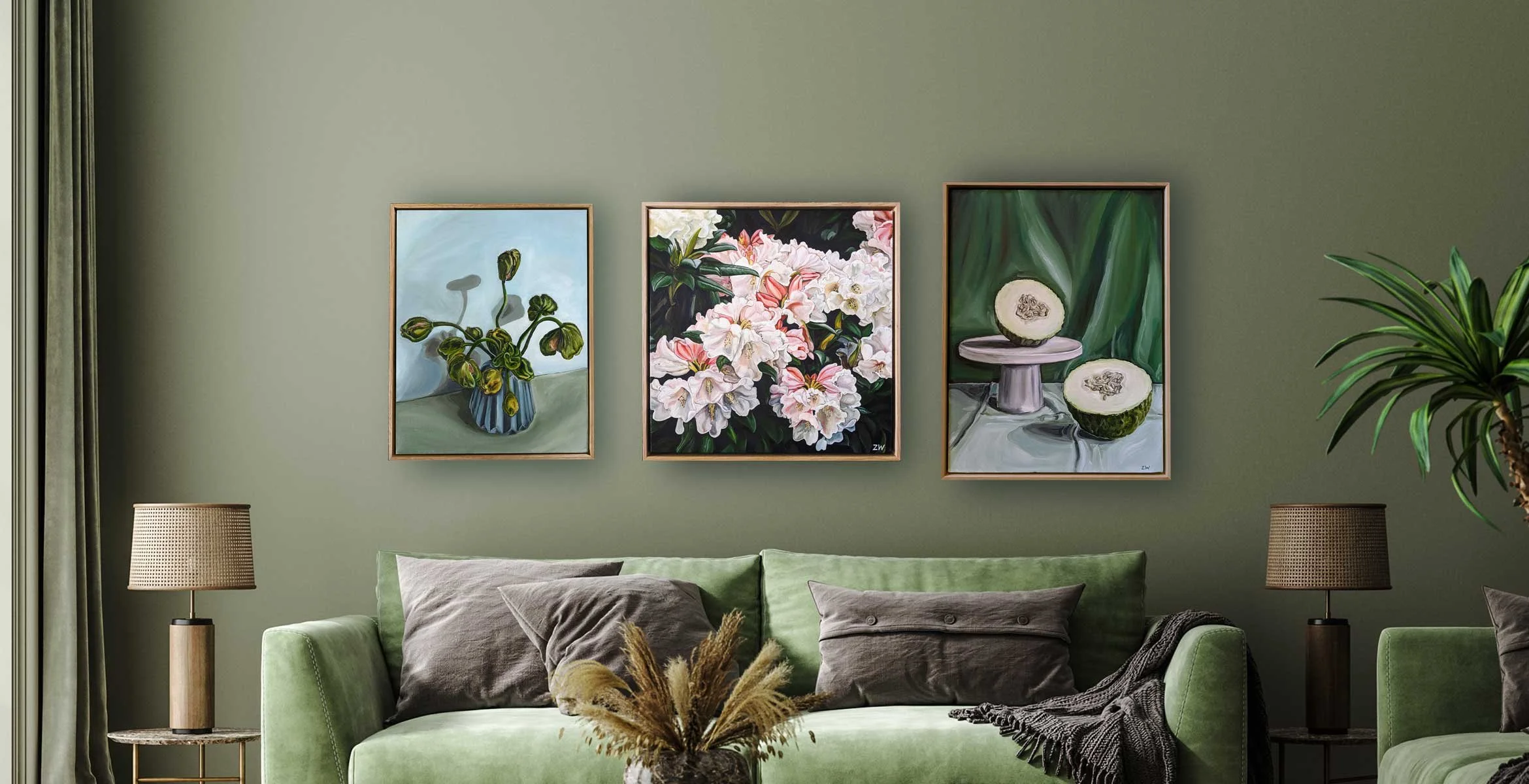 Living room with green sofa, dark brown pillows, two table lamps, framed floral artwork, and potted plant.