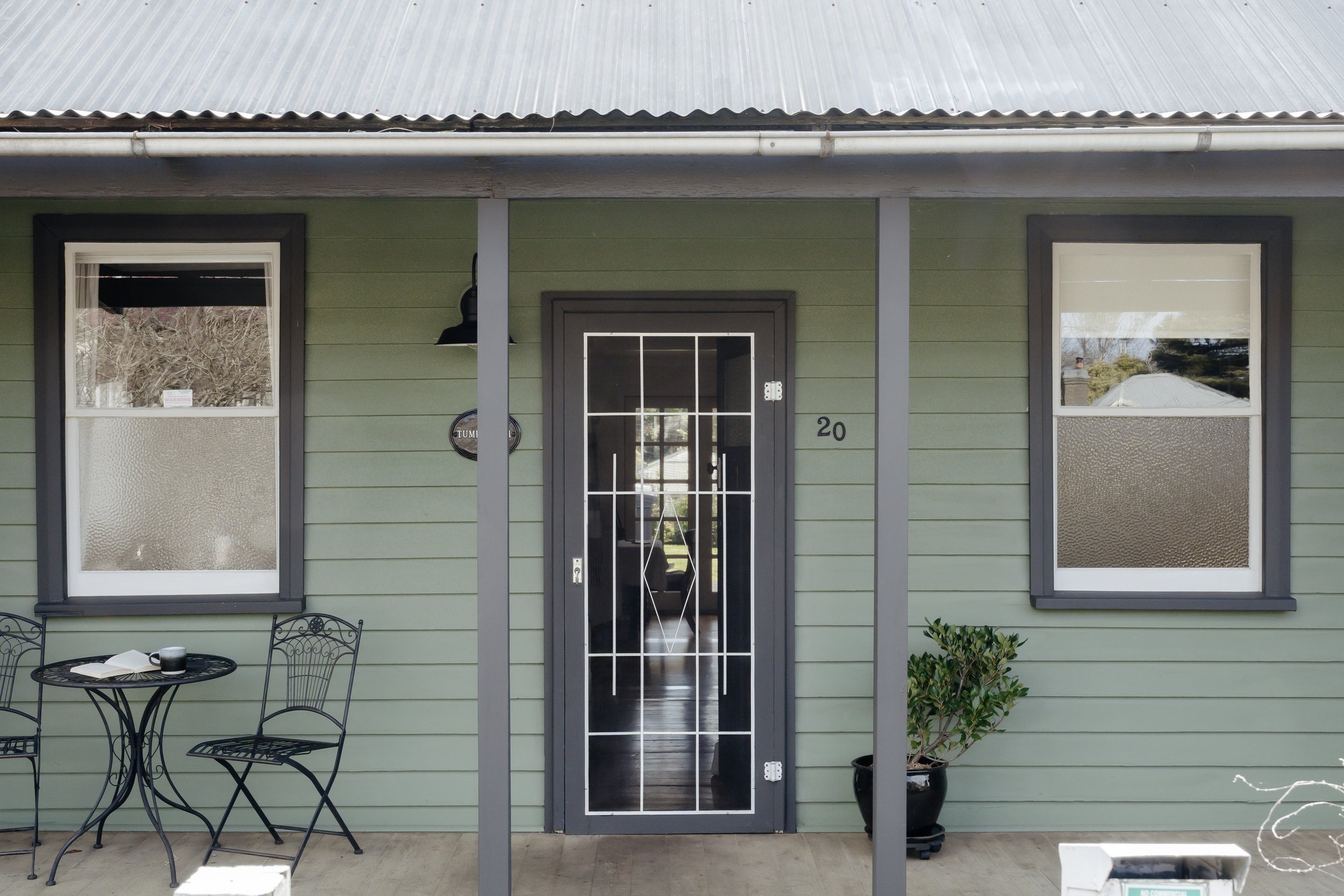 Heritage weatherboards in a gentle green, a tin roof touched by a century of seasons, and iron chairs on the verandah waiting for you to sit, sip and watch the mist move through the garden — the simple, old-world charm of mountain life at its best.