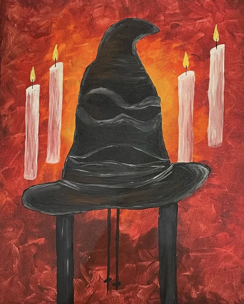 A black witch's hat on a table with three lit candles against a fiery red and orange background.
